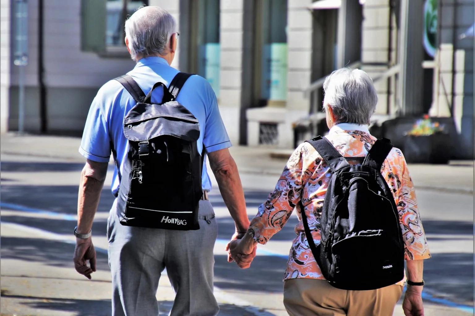 Para seniorów z plecakami idzie ulicą