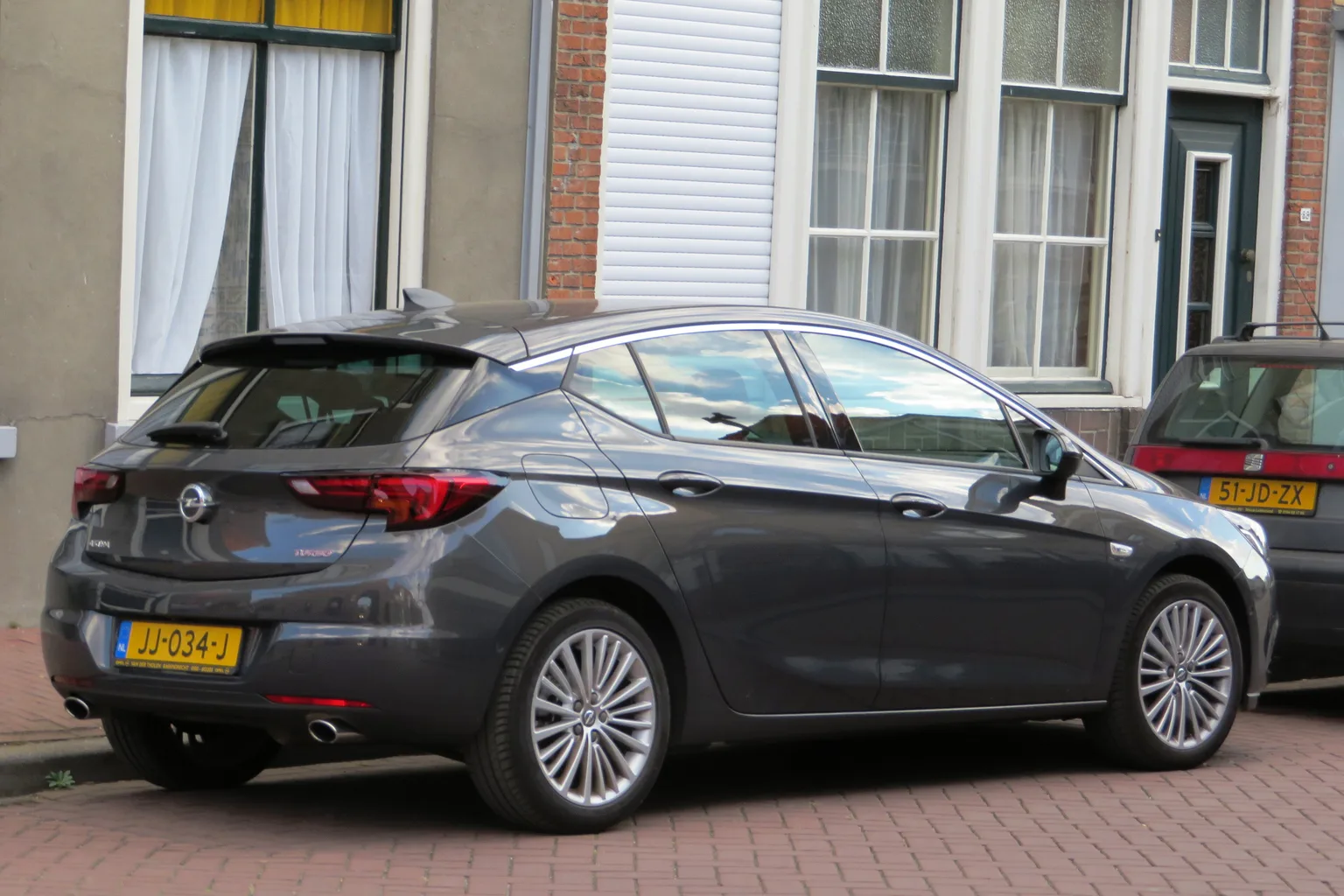 Grafitowy Opel Astra K od tyłu przy kamienicy
